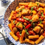 A rustic blue-speckled bowl of Chicken Cacciatore pasta, featuring rigatoni tossed with sautéed chicken, mushrooms, and bell peppers in a chunky, hunter-style tomato sauce, garnished with fresh basil.
